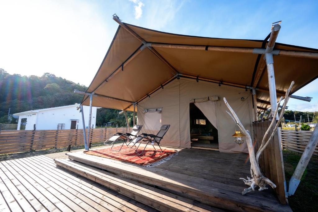 a tent with two chairs on a wooden deck at RISE BEACH Okumatsushima in Higashimatsushima