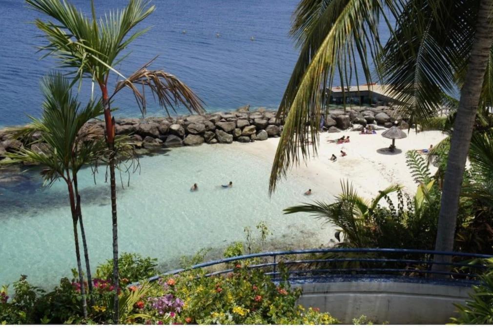 a beach with people swimming in the water at Appartement Zen et Mer des Caraïbes in Schœlcher