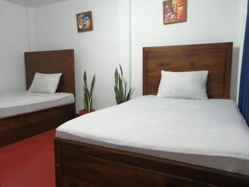 1 dormitorio con 2 camas con sábanas blancas en Sagwa en Embilipitiya