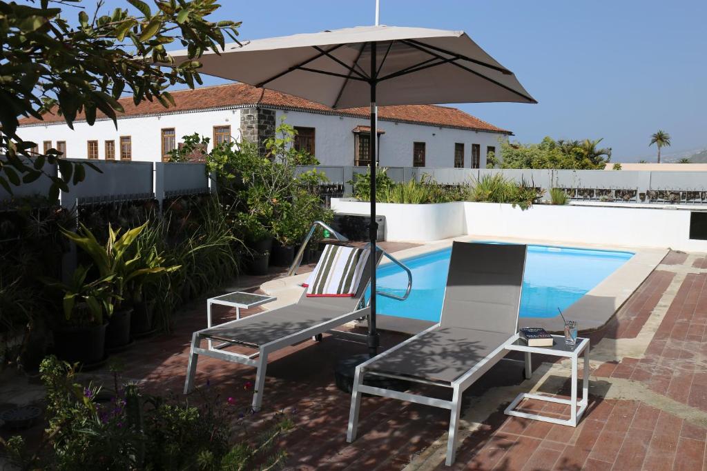 um par de cadeiras e um guarda-sol ao lado de uma piscina em Jungle Paradise em La Orotava