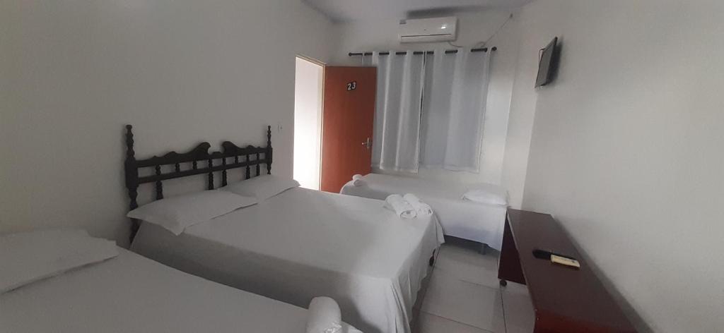 ein weißes Schlafzimmer mit 2 Betten und einem Fenster in der Unterkunft Hotel Arara Azul in Barra do Garças