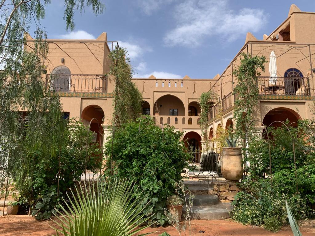 a large building with a courtyard with trees and bushes at RIAD CHANT D'ETOILES tadighoust in El Hara