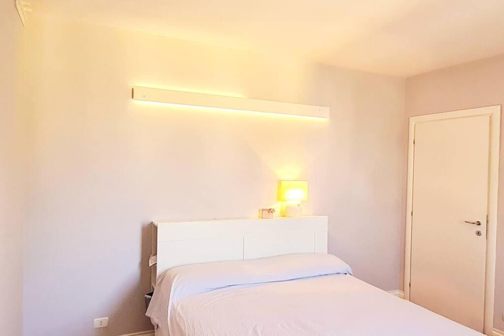 een witte slaapkamer met een bed met een licht erboven bij Verdi Valli Comfort B&B Mirandola 