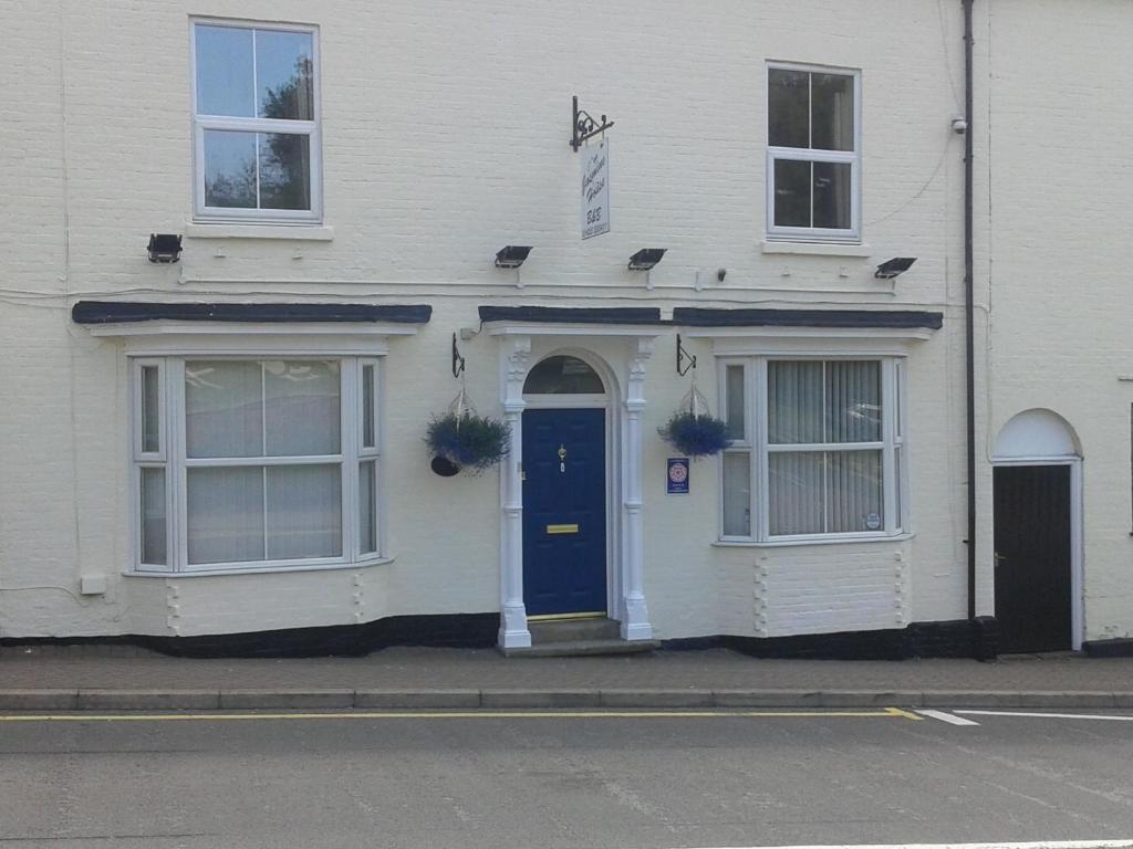 a white house with a blue door on a street at Jasmine House in Lutterworth