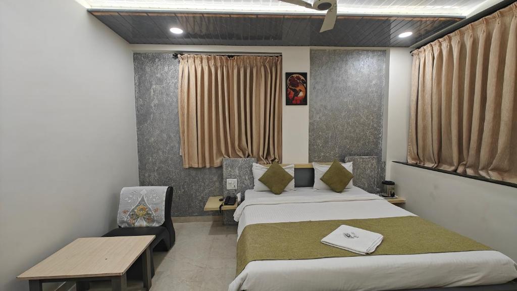 a room with two beds and a table and a desk at Cool Palace Hotels in Nashik