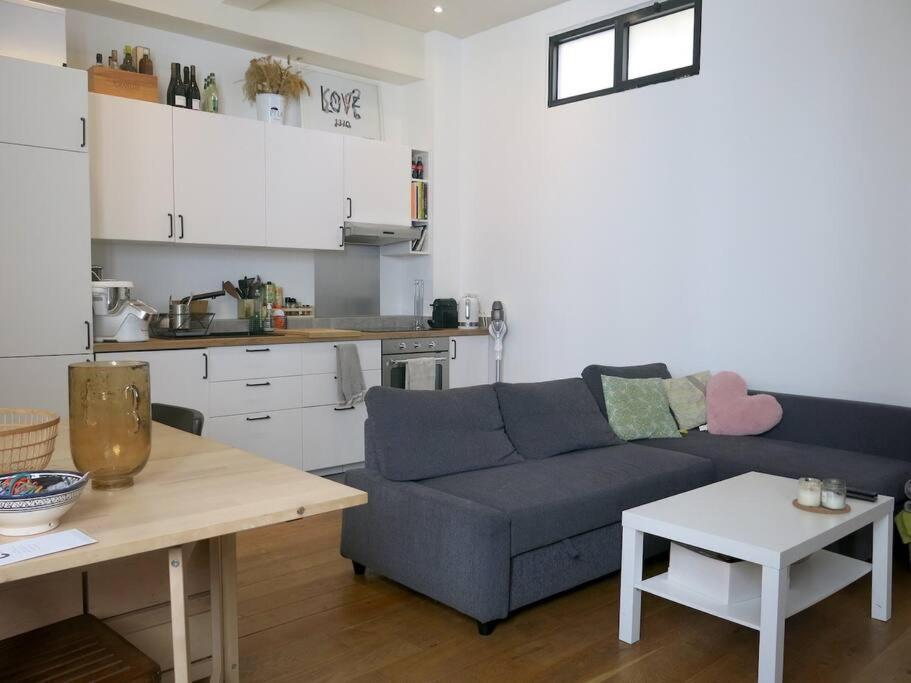 un salon avec un canapé bleu et une cuisine dans l'établissement Petit Vinaigriers République CityCosy, à Paris