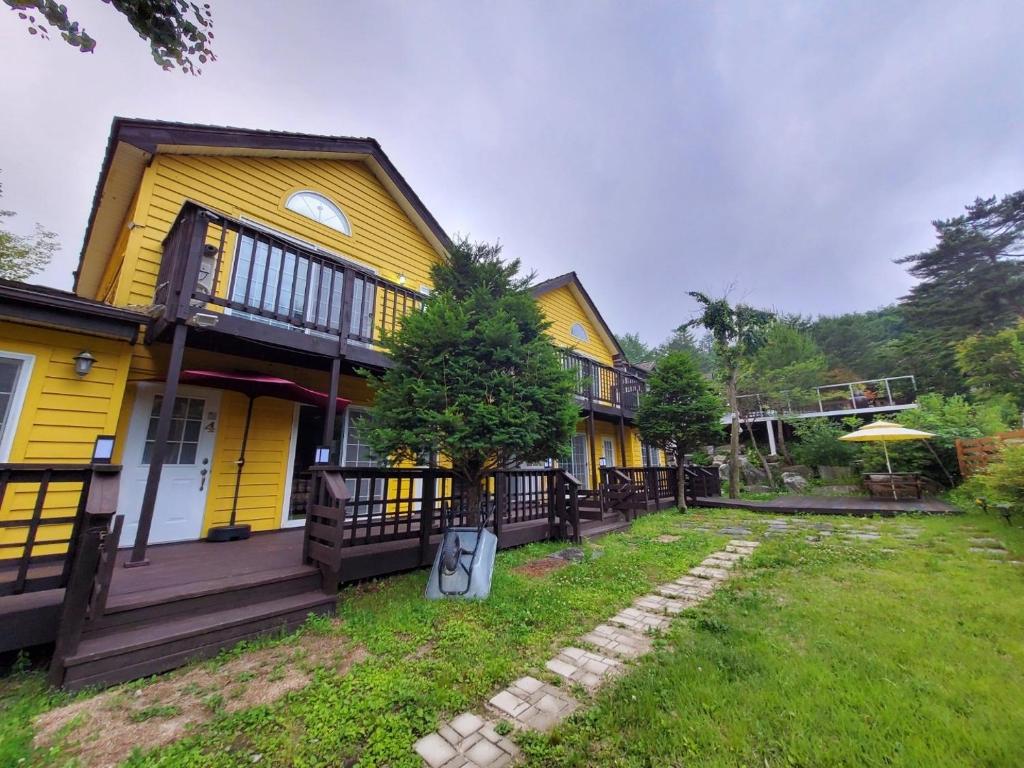 ein gelbes Haus mit einem Hof davor in der Unterkunft Honey Bear Pension in Pyeongchang