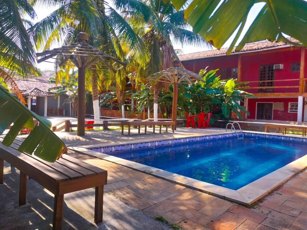 a swimming pool with a bench next to a house at Super Flats Geribá in Búzios