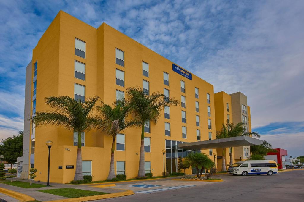 a yellow building with palm trees in front of it at City Express by Marriott Tehuacan in Tehuacán