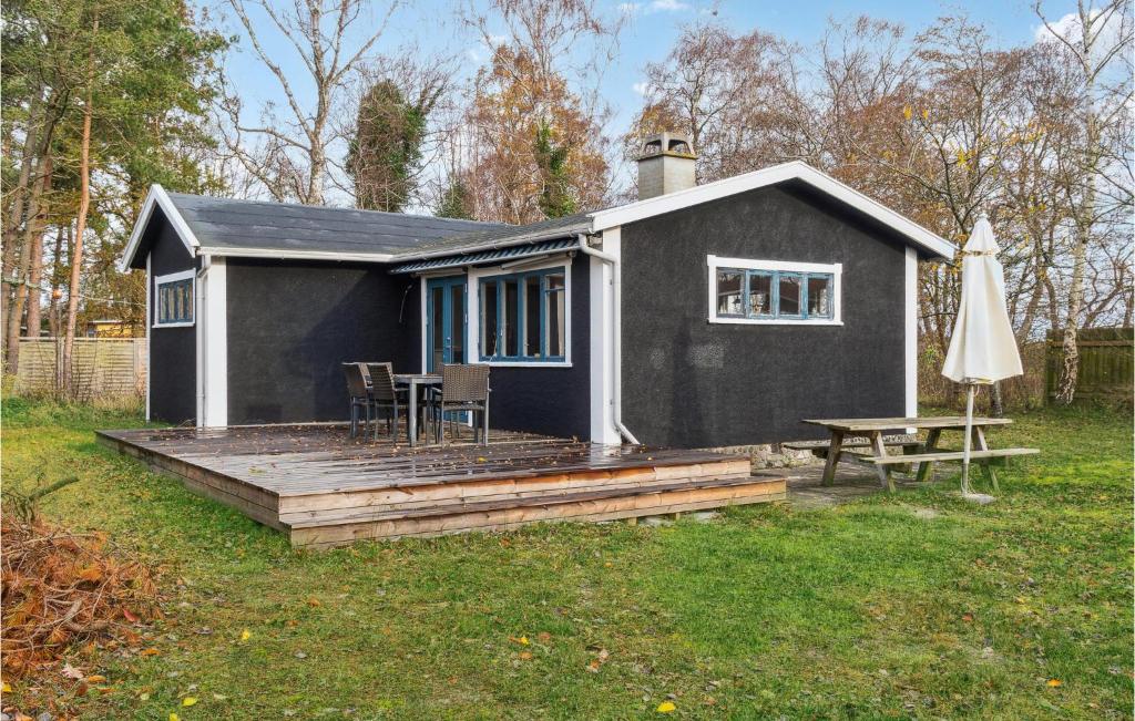 ein schwarzes Haus mit einer Terrasse, einem Tisch und einem Sonnenschirm in der Unterkunft Cozy Home In Vggerlse With Wifi in Bøtø By