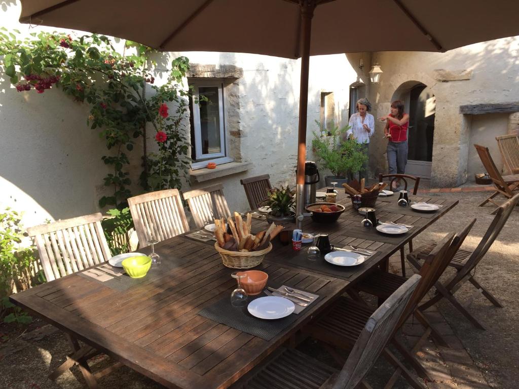 einen Holztisch mit Stühlen und einem Sonnenschirm in der Unterkunft Côté-Serein - Les chambres du Clos-Malo in Noyers-sur-Serein