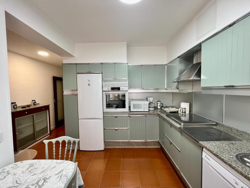 Una cocina con gabinetes verdes y un refrigerador blanco. en OLIVA 18, en Pontevedra