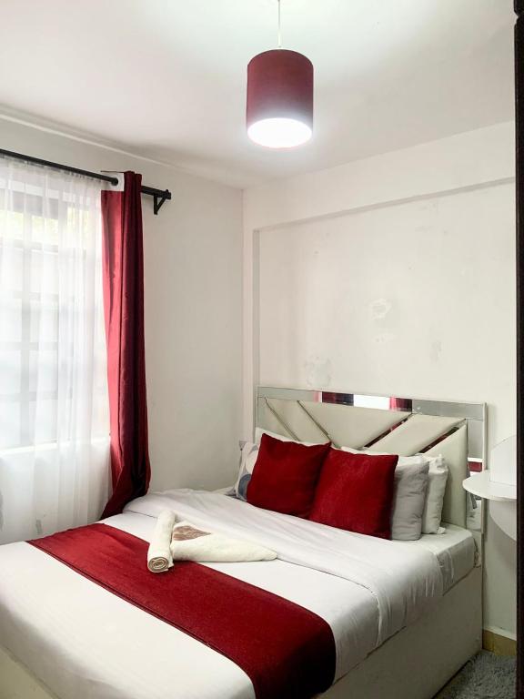 a bedroom with a large bed with red pillows at Rorot Spacious one bedroom in Kapsoya with free Wifi in Eldoret