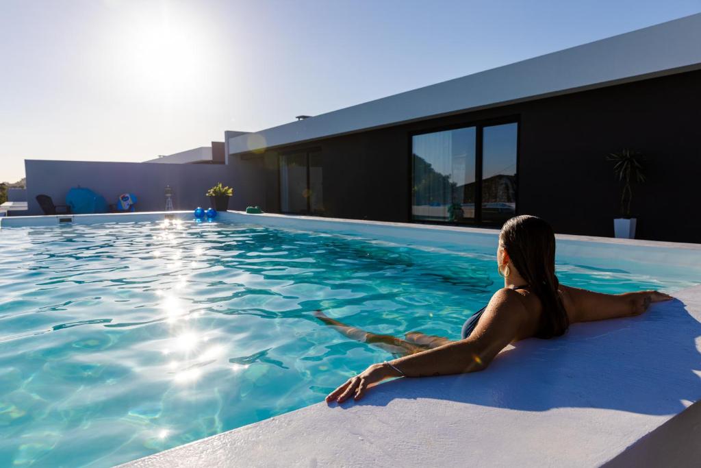 a woman laying on the edge of a swimming pool at One of a Kind #PDL Luxury Retreat in Ponta Delgada