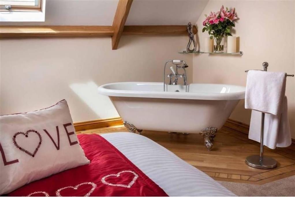 a bathroom with a tub and a bed with a love pillow at Trefaen Cottage in Brecon