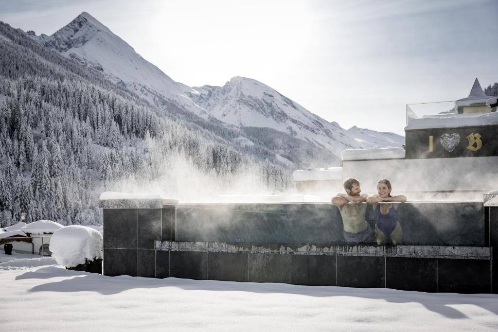 zwei Menschen stehen vor einem Brunnen im Schnee in der Unterkunft Aktiv- & Wellnesshotel Bergfried in Tux