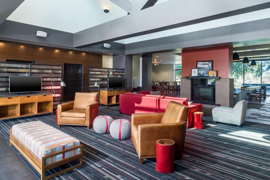 メサにあるFour Points by Sheraton at Phoenix Mesa Gateway Airportのソファ、椅子、テレビ付きの図書室