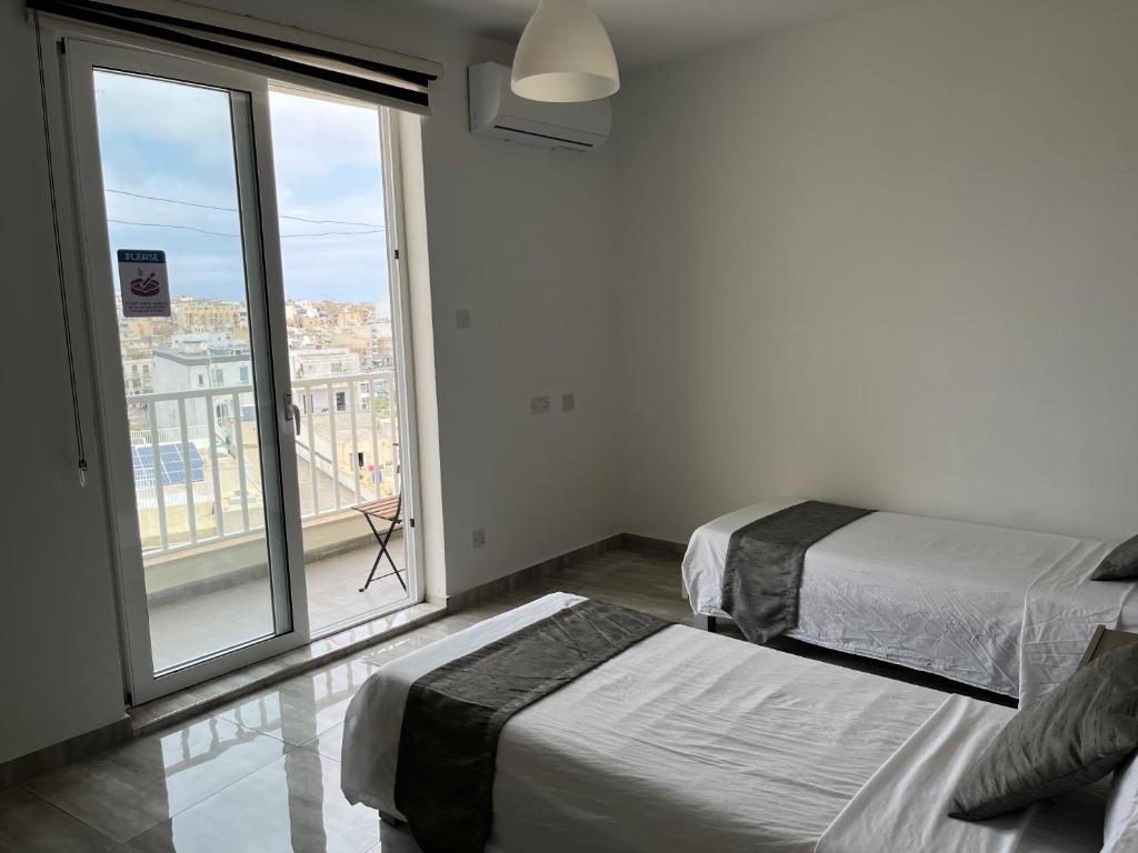 1 Schlafzimmer mit 2 Betten und einem großen Fenster in der Unterkunft F10 Modern and Bright Apartment in Malta in Msida