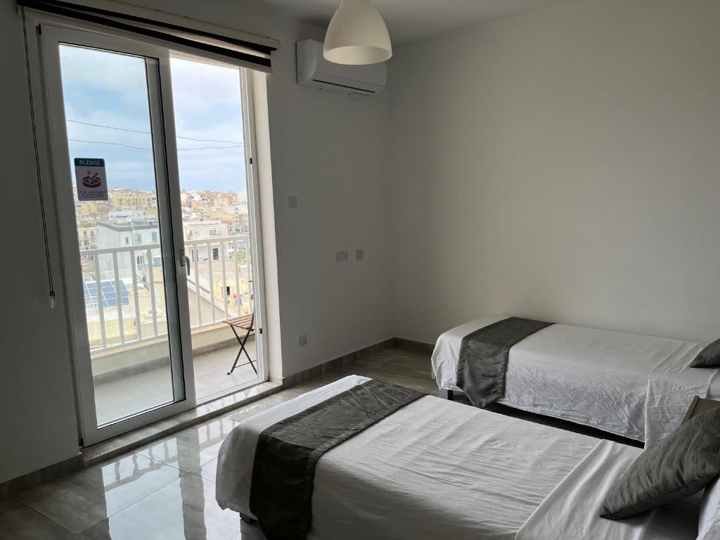 a bedroom with two beds and a large window at F10 Modern and Bright Apartment in Malta in Msida