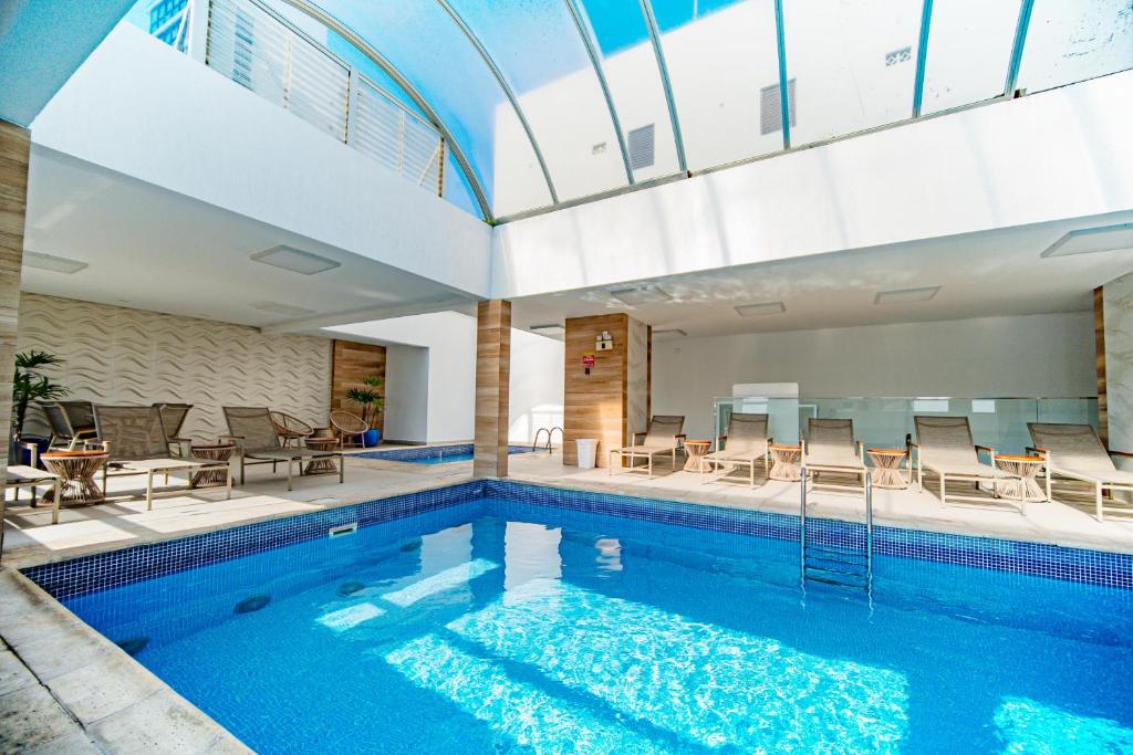 a swimming pool with chairs and tables in a building at Hotel Plaza Camboriú in Balneário Camboriú