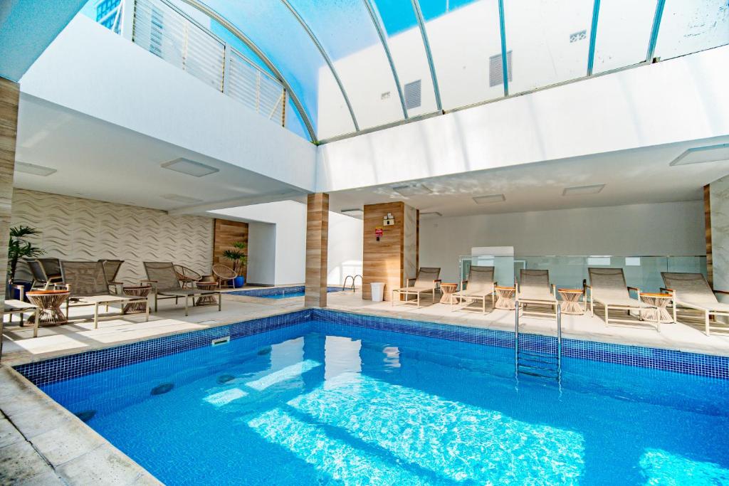 uma piscina com cadeiras e mesas num edifício em Hotel Plaza Camboriú em Balneário Camboriú