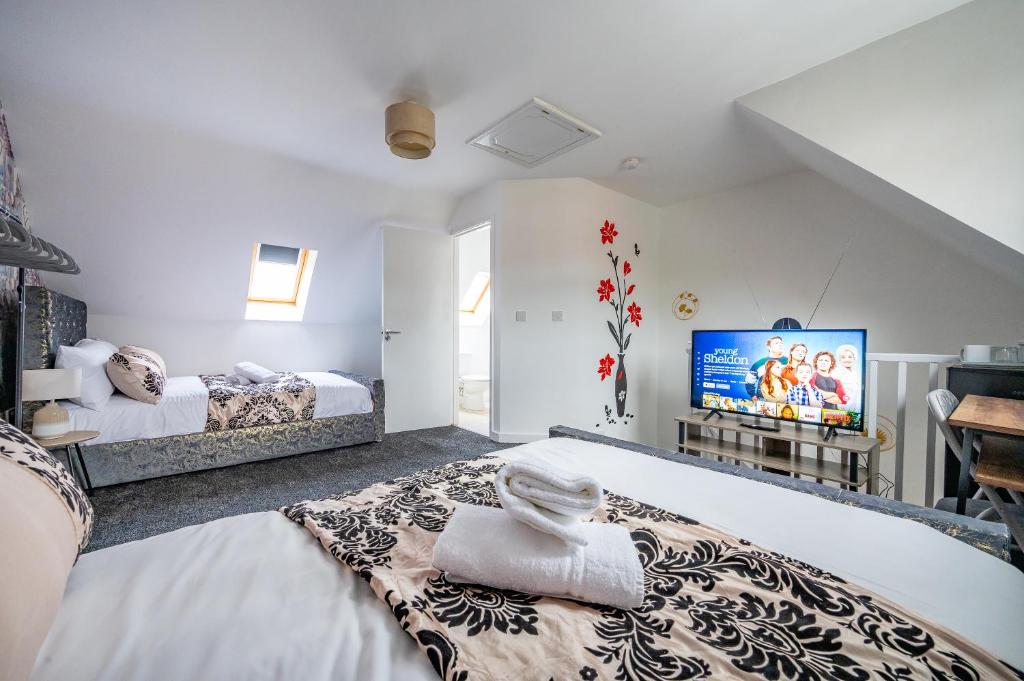Habitación blanca con 2 camas y TV. en *RA27R* For your most relaxed & Cosy stay + Free Parking + Free Fast WiFi * en Kirkstall