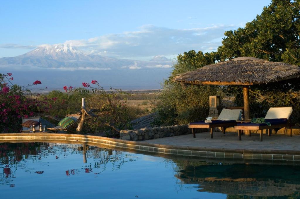 - une piscine avec une table, des chaises et un parasol dans l'établissement Kia Lodge, à Arusha