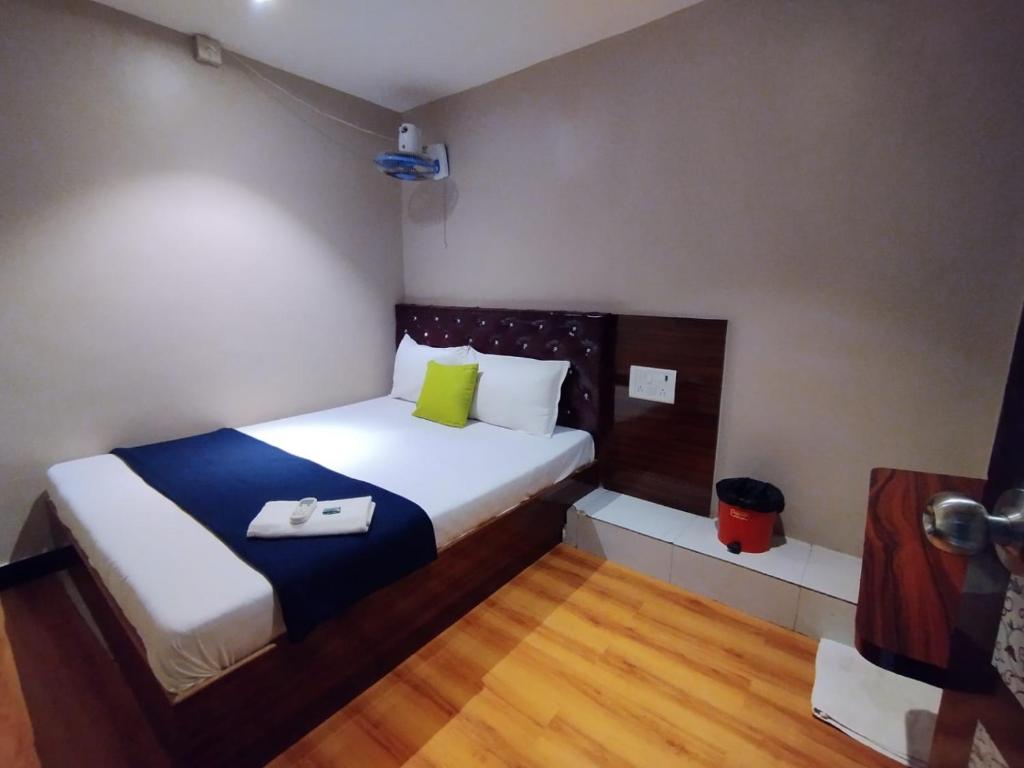 Dormitorio pequeño con cama blanca y almohadas verdes en Hotel Aspen - Near International Airport en Bombay