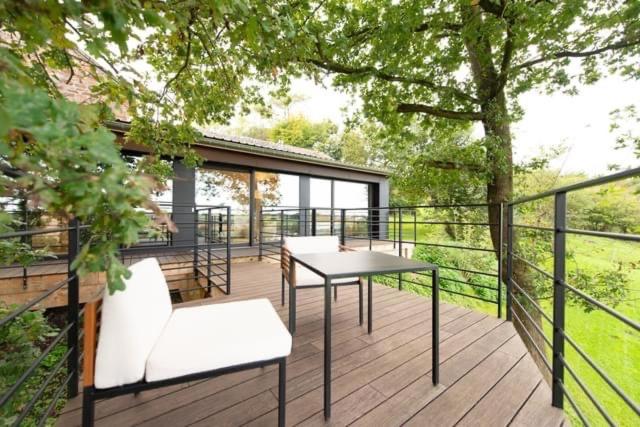 una terraza con mesa, sillas y un árbol en Gîte : Le Petit Appentis en Profondeville