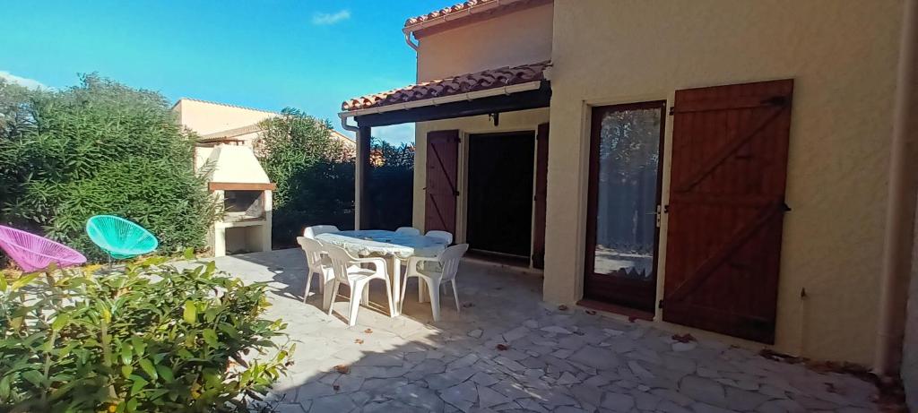une terrasse avec une table et des chaises ainsi qu'une maison dans l'établissement LE LAGON Maison avec immense terrasse - piscine partagée et plage à 300 m, à Saint-Cyprien