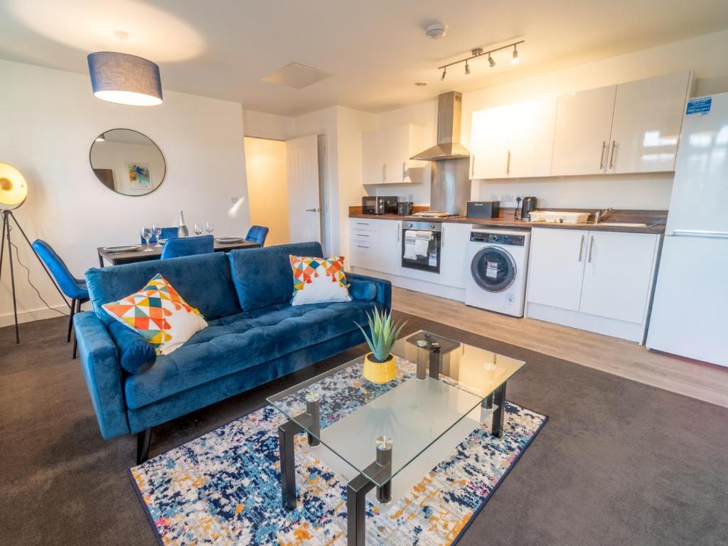 a living room with a blue couch and a kitchen at Pass the Keys Beautiful 1 bedroom apartment in Nottingham