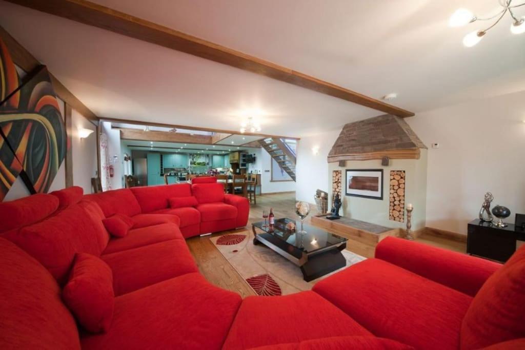 un soggiorno con divano rosso e camino di Oak Barn a Brecon