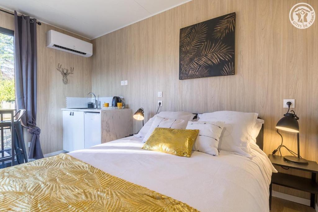 1 dormitorio con 1 cama blanca grande y almohada de oro en La cabane du pecheur, en Aix-les-Bains