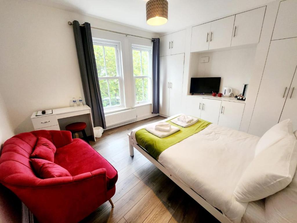 1 dormitorio con 1 cama y 1 silla roja en Old Victory House Homestay en Portsmouth