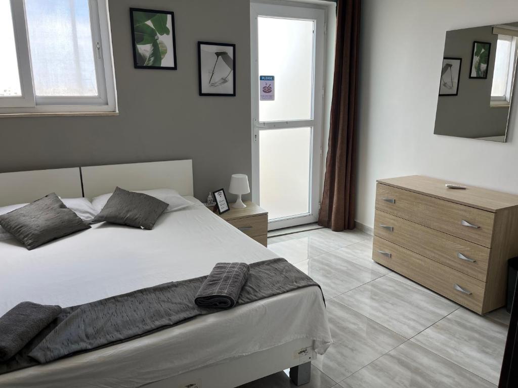 a bedroom with a bed and a dresser and a window at F5-1 Double room with private bathroom and balcony in shared Flat in Msida