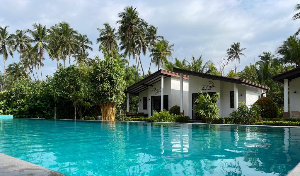 a swimming pool in front of a house with palm trees at Sanda Eliya Resort in Bentota