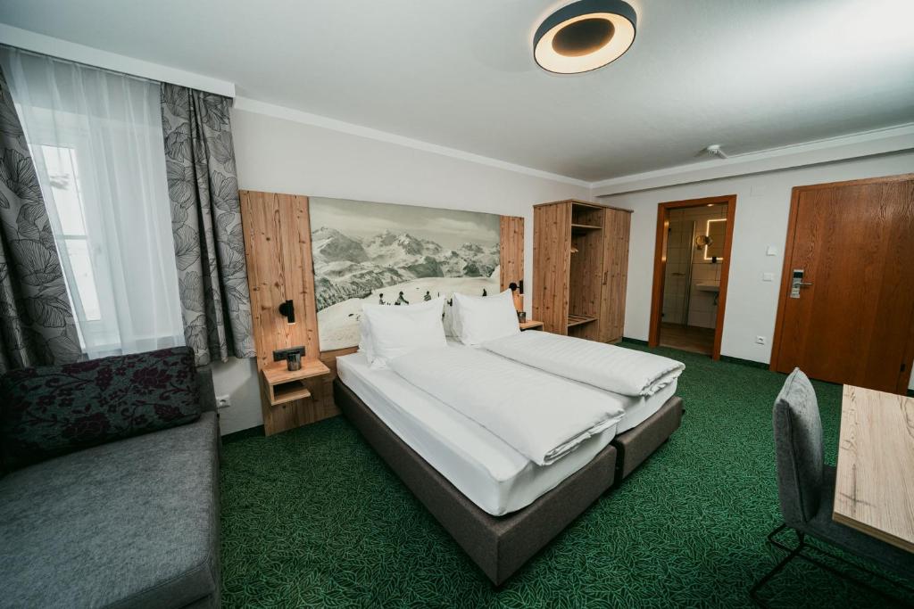 um quarto com uma grande cama branca e um sofá em Apparthotel Samson em Obertauern