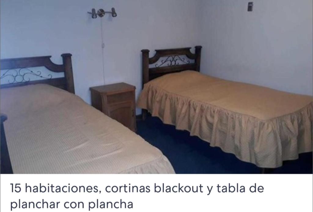 a room with two beds and a table and avertisement at Hotel Oasisa in Uyuni