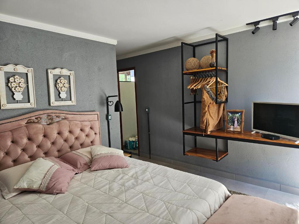 a bedroom with a large bed and a television at CASA DINAMARCA in Santa Teresa