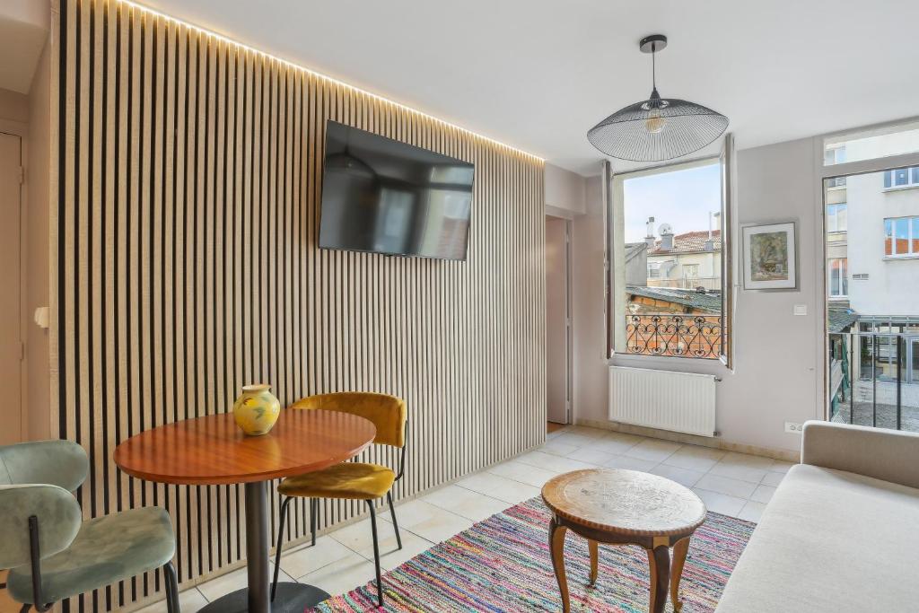 ein Wohnzimmer mit einem Tisch und einem TV an der Wand in der Unterkunft Hôtel Robespierre Ex Idéal hôtel Paris - Montreuil in Montreuil