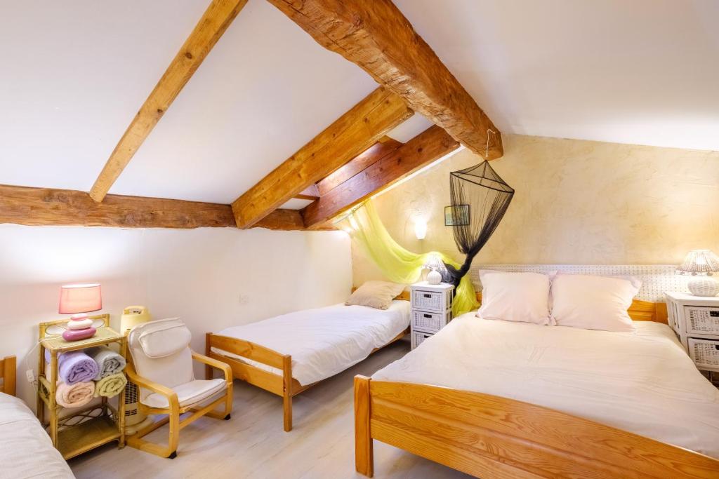 two beds in a room with wooden ceilings at Villa Provence Vue Panoramique - in Fayence