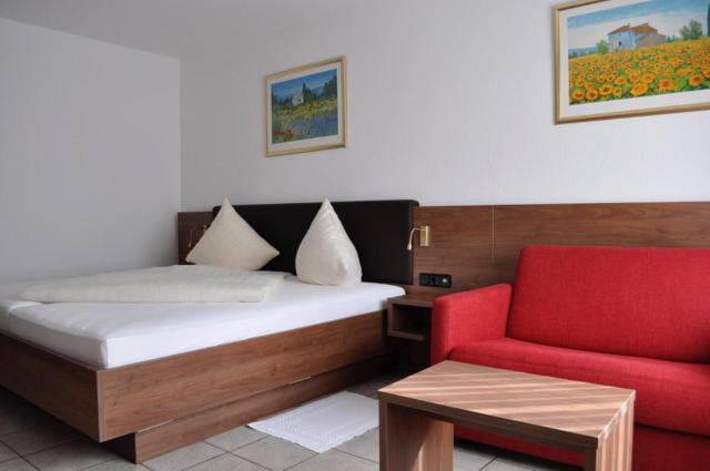 a bedroom with a bed and a red chair at Hotel Europa in Ramstein-Miesenbach