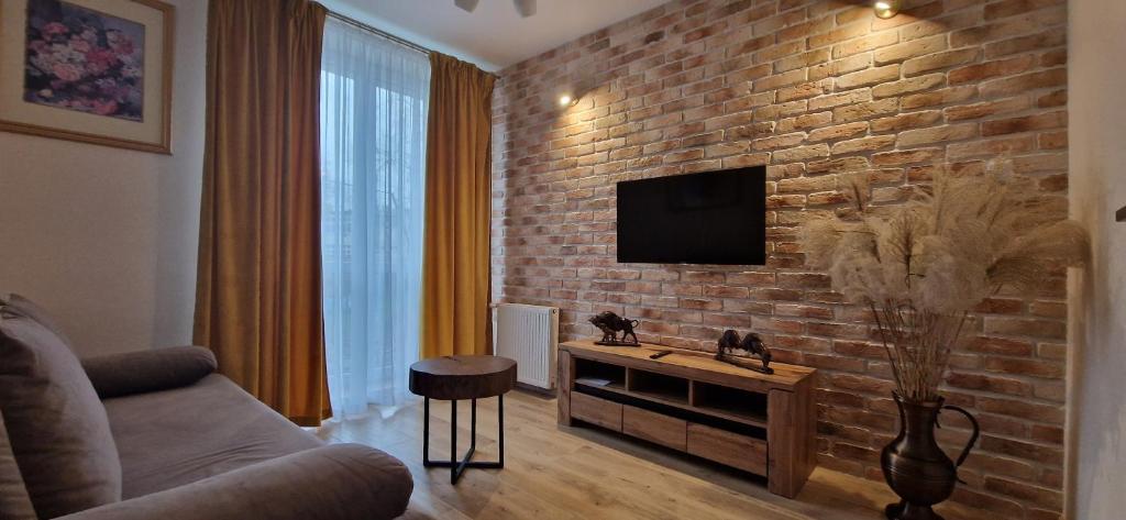 ein Wohnzimmer mit einer Ziegelwand und einem TV in der Unterkunft Noclegi na Ogrodowej in Sandomierz
