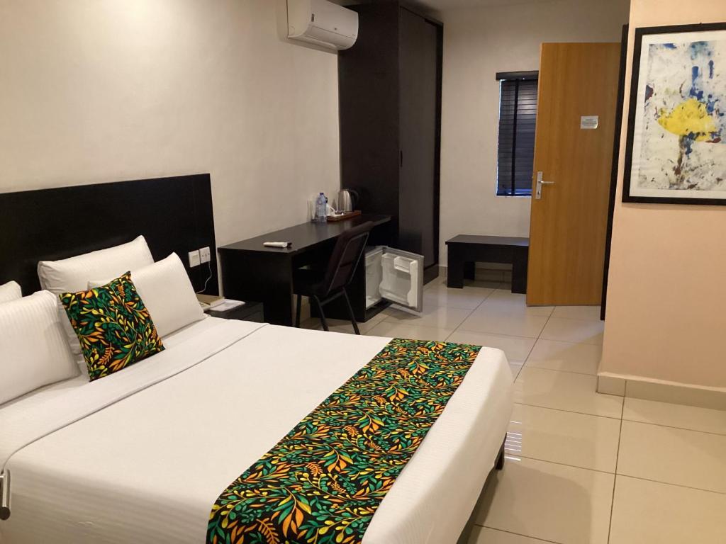 a bedroom with a bed and a desk in a room at Adis Hotels Prime in Ibadan