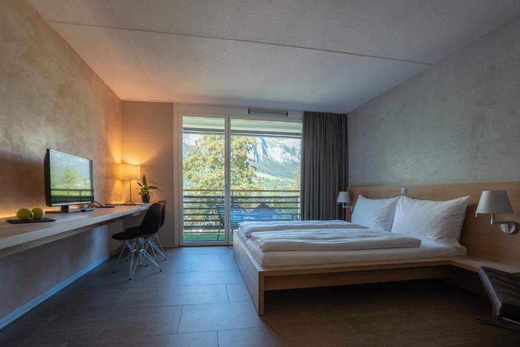 una camera d'albergo con un letto, una scrivania e una finestra di Hotel des Alpes a Flims