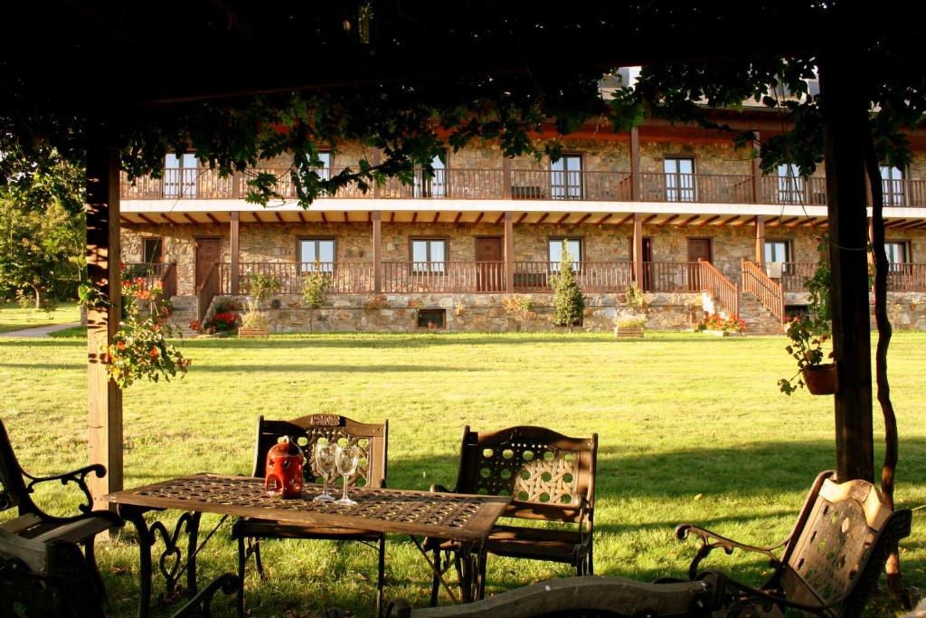 een tafel en stoelen in een veld met een gebouw bij Alojamiento en entorno rural Los Trobos in Villar de Otero