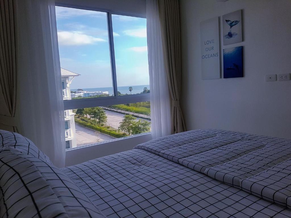 a bedroom with a bed and a large window at Energy Seaside city Hua-Hin / Cha-am in Ban Bo Khaem