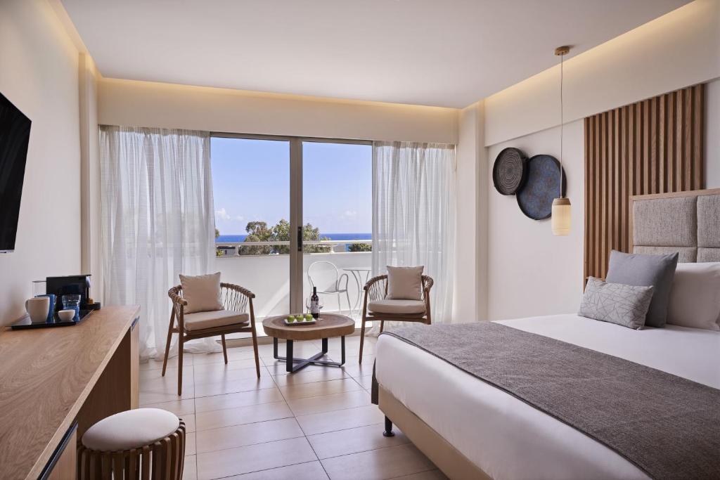 a hotel room with a bed and a table and chairs at Atlantica Bay - Adults Only in Limassol