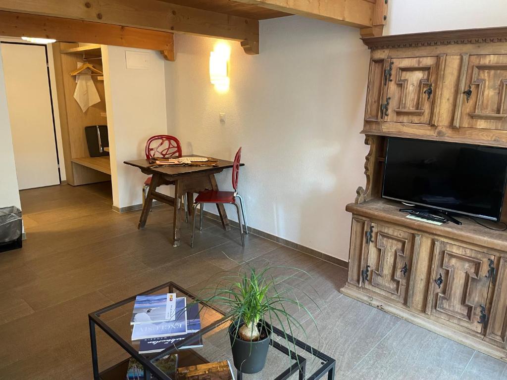 un soggiorno con grande TV e tavolo di Hotel des Alpes a Flims