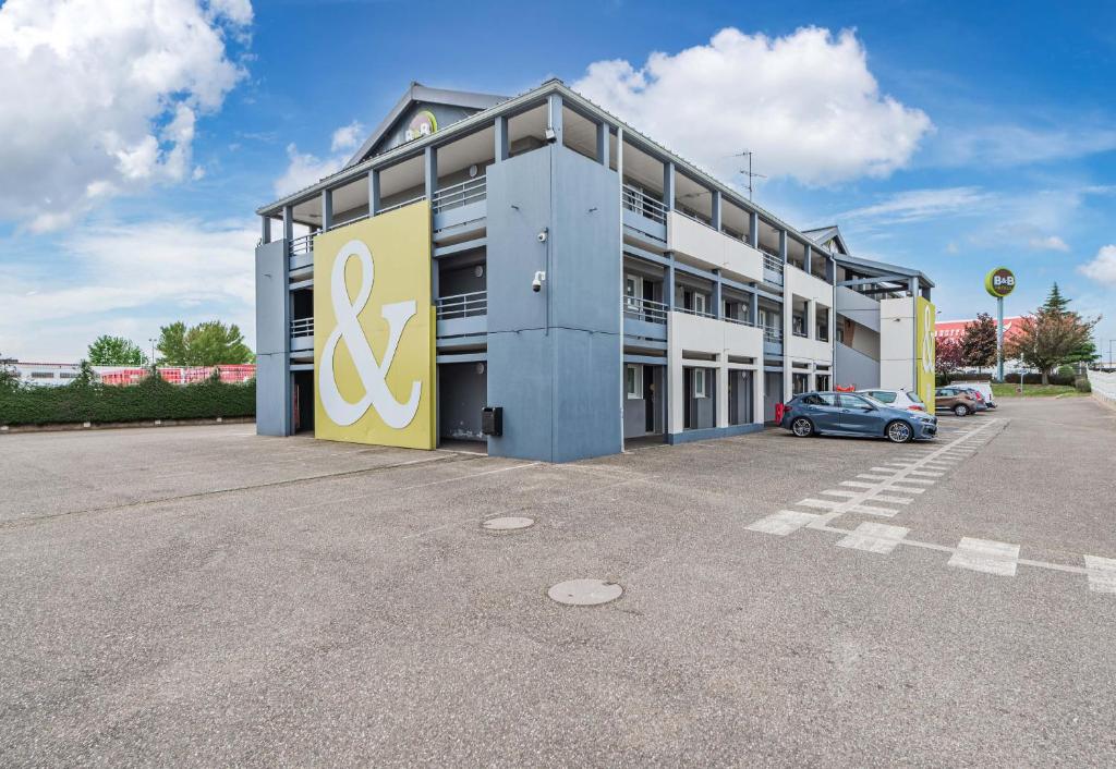 um grande edifício com um carro estacionado num parque de estacionamento em B&B HOTEL STRASBOURG Nord Industrie em Vendenheim